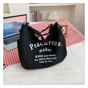 Detailed view of black canvas bag with white text print on indoor desk with laptop