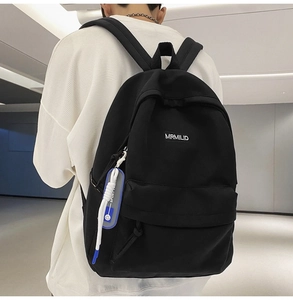 Rear side view of a minimalist black backpack with MRMILID logo and blue woven keychain tag