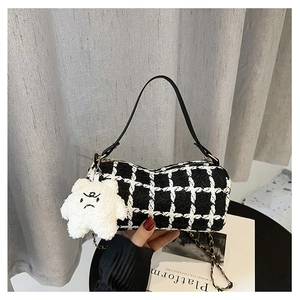 Detail of black and white tweed crossbody bag featuring a plush star charm and gold chain strap