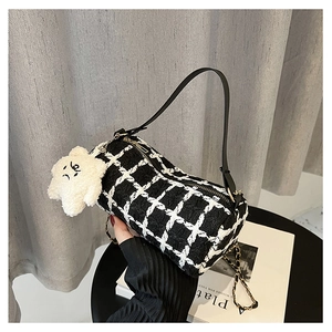 Close-up of black and white plaid cylinder bag with star plush charm and chain strap