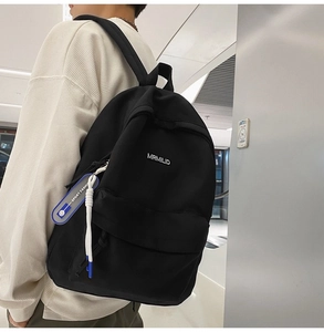Side view of minimalist black nylon backpack featuring a white logo and blue sport keychain