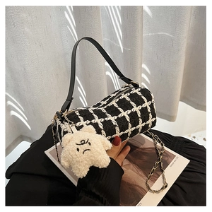 Detail of checkered tweed Boston bag with plush star charm and leather strap handles