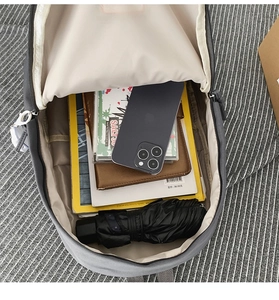 Spacious interior of grey backpack showing storage for books, smartphone, and a folded umbrella