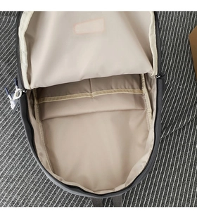 Internal view of minimalist grey backpack showing beige lining and functional pockets
