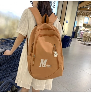 Caramel retro college style backpack with white bear pendant shown in a shopping scene