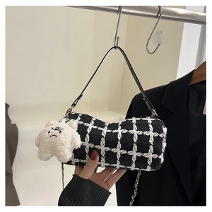Detail of tweed checkered bag featuring leather strap, metal chain, and plush star charm
