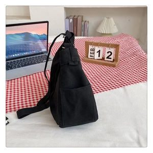 Detailed macro view of the black canvas crossbody bag showing side pocket and wide strap