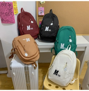 Close-up of colorful nylon school backpacks featuring cute bear pendants and M RMI logos