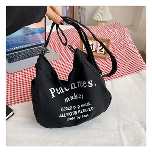 Detail of black canvas tote bag with white text print and adjustable shoulder strap