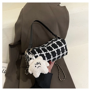 Detail of checkered cylinder bag with tweed texture, chain strap and star plush charm