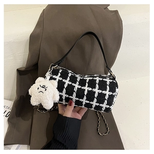 Detail of black and white checkered tweed baguette bag with plush star charm
