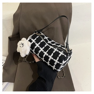 Close-up of black and white checkered tweed Boston bag with chain strap and bear charm