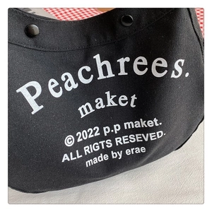 Detail of black canvas tote showing heavy-duty fabric texture and metal snap button