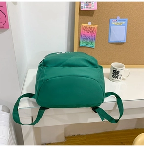Detailed close-up of a green nylon laptop backpack on a desk with lifestyle props