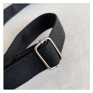 Detail of adjustable black canvas strap with silver metal buckle on the handbag