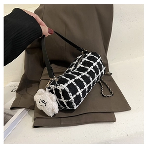 Detailed close-up of a black and white checkered cylinder bag with a plush bear charm