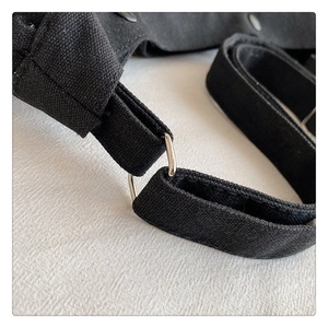 Close-up of black canvas bag strap connection with a silver metal ring and fabric texture