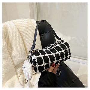 Detail of black and white tweed cylinder bag with gold chain and plush charm