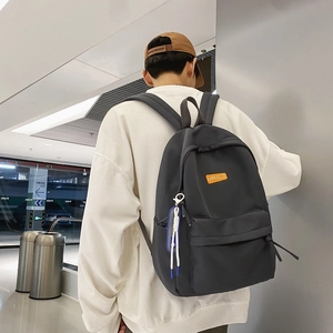 Minimalist dark gray waterproof backpack with orange silicone label and decorative lanyard