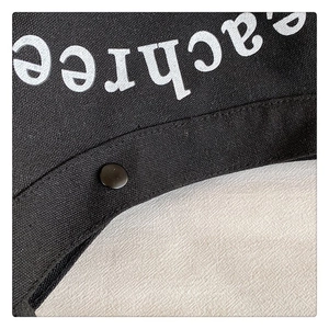 Detail view of black canvas bag featuring a snap button closure and white printed text