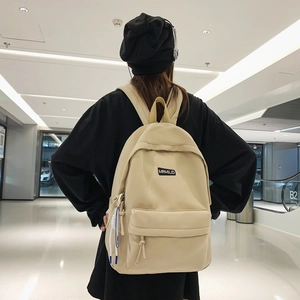 Minimalist beige backpack with MRMILID label shown from behind on a model in urban setting