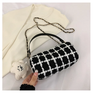 Detail of checkered tweed cylinder bag featuring leather handles and a plush star charm
