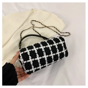 Detail of black and white tweed cylindrical handbag with gold chain strap and leather handle