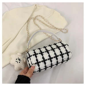 Detail of tweed checkered cylindrical bag with golden chain and star charm