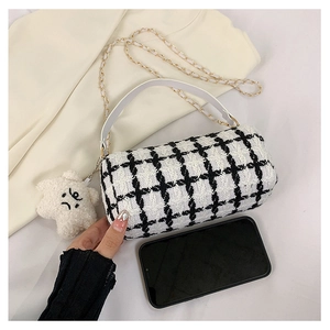 Detail view of mini black and white plaid tweed cylinder bag with white leather handle