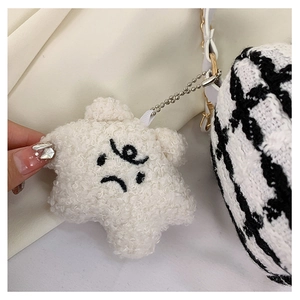 Close-up of a white plush star pendant with embroidery on a houndstooth pattern bag