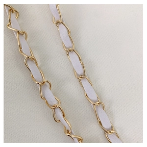 Detail of white leather interwoven with golden metal chain strap on minimalist bag