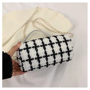 Detail view of black and white tweed crossbody bag with gold chain and leather handle