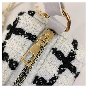 Close-up of golden metal zipper and black and white houndstooth fabric on small handbag