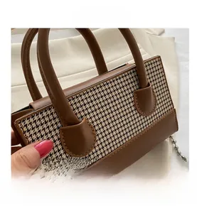 Detail shot of checkered texture and brown leather with detachable metal ball chain strap