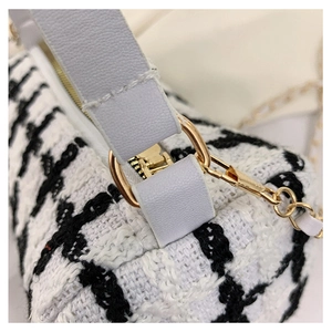 Detail of black and white tweed fabric with gold hardware on a woman small square bag