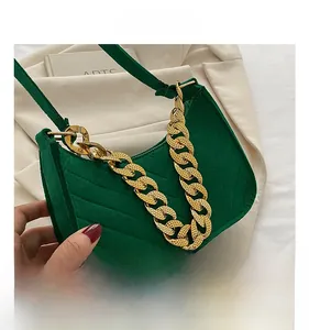 Close-up of green suede baguette bag with V-shaped quilting and thick gold chain link