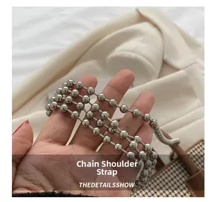 Close-up of a silver beaded metal chain strap on a checkered pattern shoulder bag