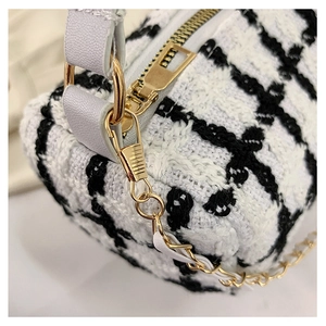 Close-up of black and white tweed fabric texture with premium golden metal hardware