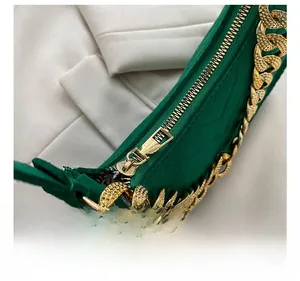 Close-up of golden metal zipper and chunky chain strap on a green suede shoulder bag