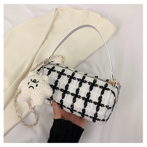 Detail of tweed checkered cylinder bag with leather handle and star charm