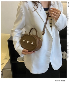 Détail du sac bandoulière marron avec fleurs blanches et finitions métalliques dorées