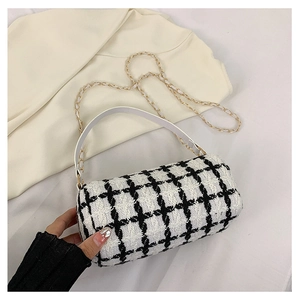 Detailed close-up of a cylinder plaid tweed handbag with metal chain and leather handle