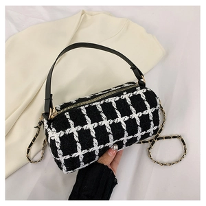 Detail of black and white tweed boston bag with gold chain strap and leather handle