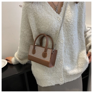 Detail of mini checkered crossbody bag with beaded chain strap on a white knit cardigan