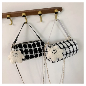 Macro view of checkered tweed cylinder bags with plush star charms and golden chain straps