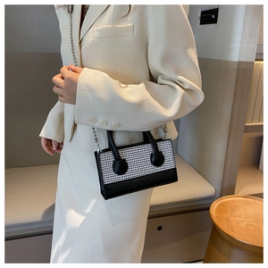 Detail of checkered crossbody bag with silver chain strap on cream blazer