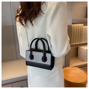 Detail of checkered crossbody bag with silver chain strap and leather handle