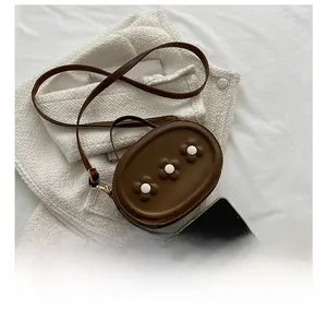 Détail d'un sac bandoulière ovale en cuir PU marron orné de trois fleurs décoratives en 3D