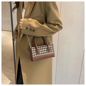 Detail showing checkered pattern stitching and silver bead chain strap on crossbody bag