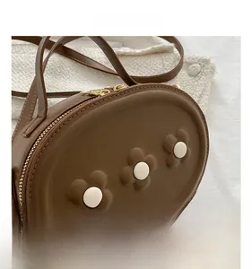 Détail du sac bandoulière en cuir PU marron avec trois fleurs 3D et double fermeture éclair
